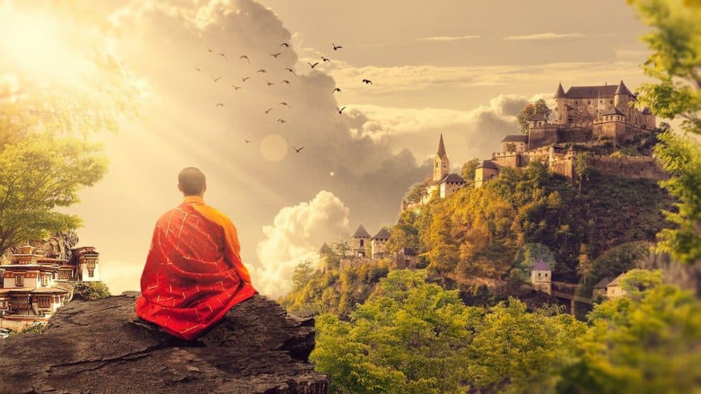 Buddhist monk sitting at the edge of a mountain