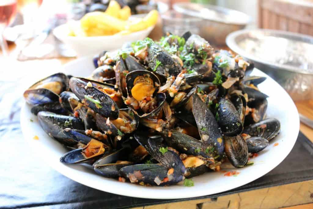 Cooked mussels with spices and herbs on a white platter