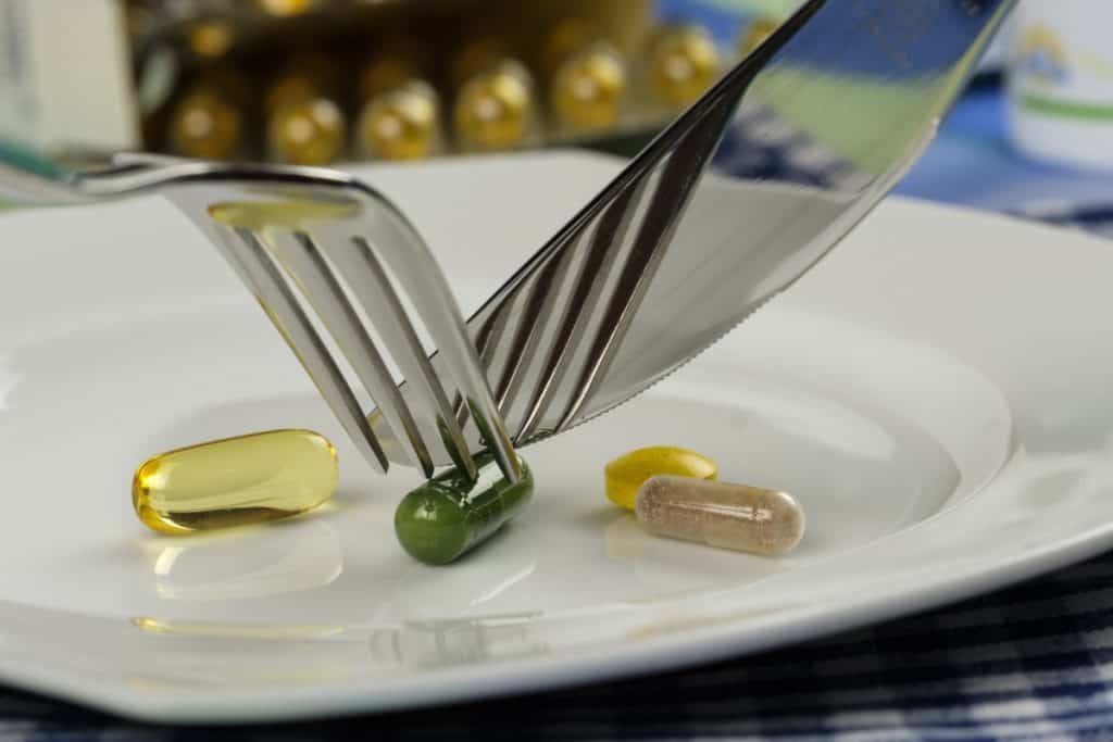 Supplements as meal on a plate, eating with fork and knife
