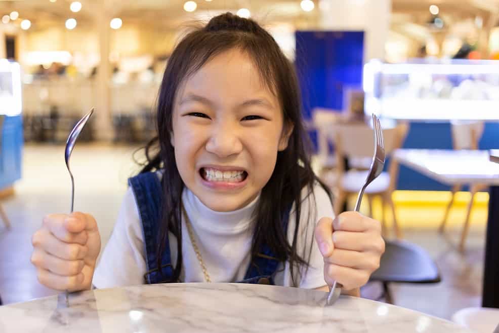 Hangry girl at eating table